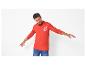 Homme en polo rouge à manches longues avec motif ancre et jean bleu.