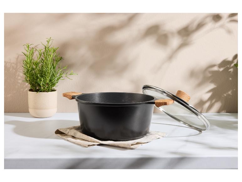 Marmite noire avec poignées en bois et couvercle en verre, avec une plante de romarin à côté