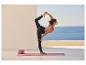 Femme en posture de yoga sur un tapis avec des blocs de yoga, vue sur la mer.