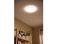 Een heldere, ronde plafondlamp verlicht een kamer met een houten plank en decoratie.
