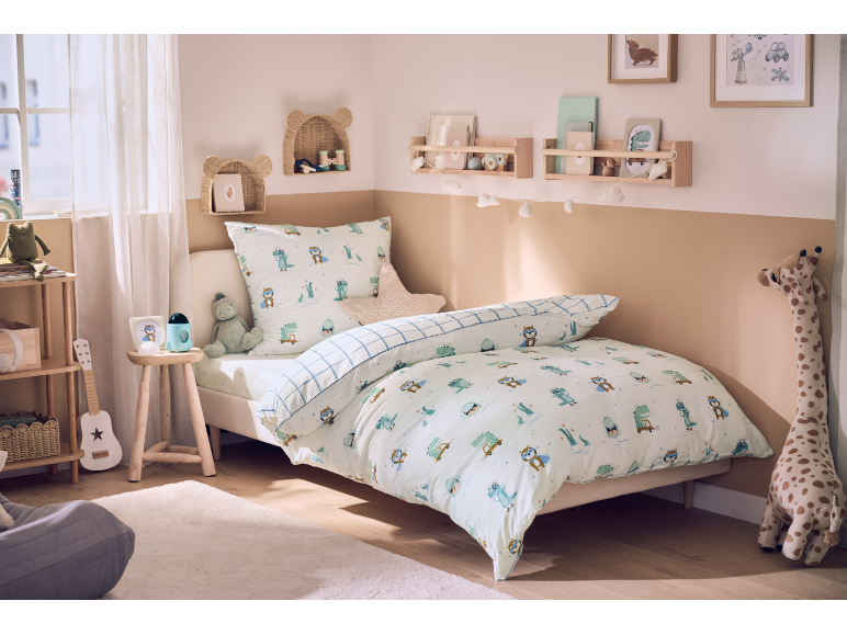 Chambre d'enfant chaleureuse avec un lit paré d'une parure de lit dinosaure et une déco ludique.