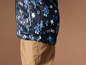 Een donkerblauwe jas met robotprint en bruine broek.