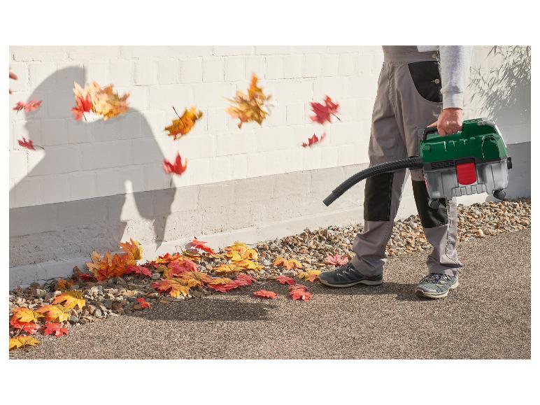 Homme utilisant un souffleur de feuilles pour nettoyer les feuilles d'automne d'une allée.