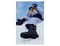 Une personne en pantalon de ski violet et bottes de neige bleu foncé assise dans la neige.