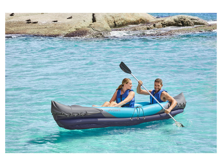 Een stel peddelt in een opblaasbaar kajak van Crivit in turquoise water.