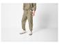 Homme en survêtement kaki, avec pantalon de survêtement et sweat-shirt, portant des baskets blanches.