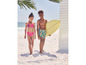 Deux enfants sur la plage, une fille en bikini et un garçon avec une planche de surf.