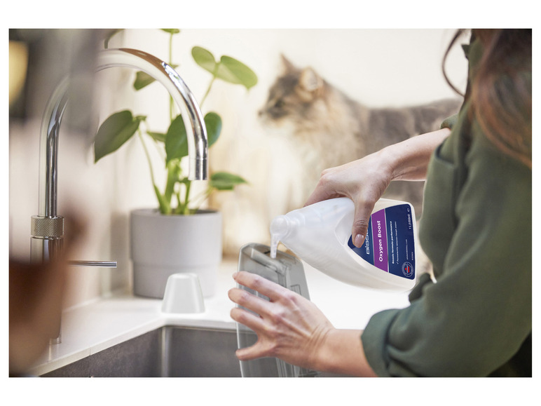 Une femme verse du Bissell Oxygen Boost dans un appareil de nettoyage.