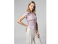 Een vrouw draagt een roze T-shirt met print en witte broek.