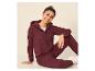 Jeune femme souriante en sweat à capuche et pantalon de jogging bordeaux.
