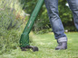 Une personne utilisant une débroussailleuse Parkside pour tondre l'herbe.