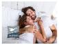 Gelukkig stel omhelst elkaar in bed, met Häussling-logo.