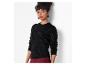 Femme en pull noir scintillant et pantalon bordeaux.