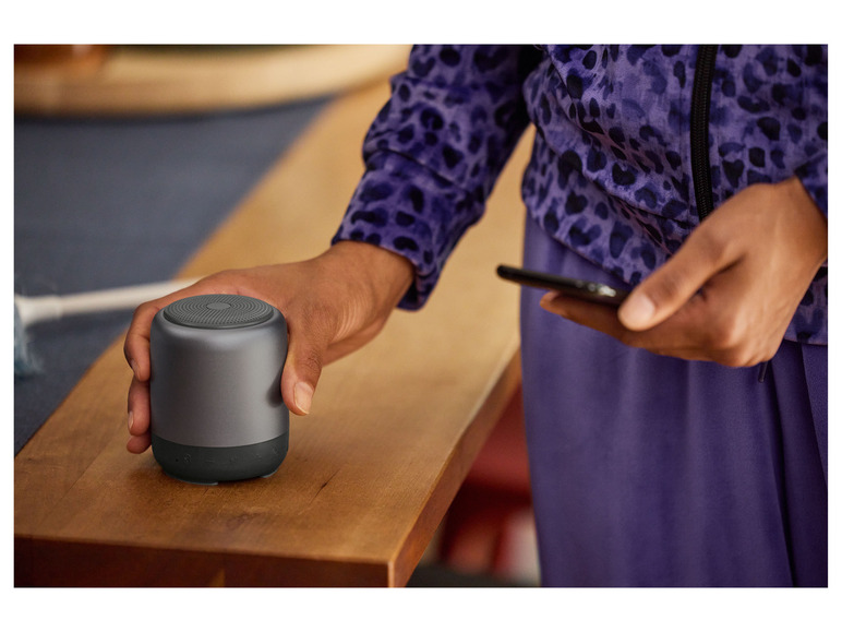Een hand houdt een draagbare Bluetooth-luidspreker vast.