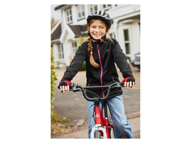 Fille souriante avec un casque de vélo et une veste sur un vélo rouge.