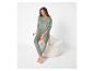Vrouw in groene velours pyjama met stippen, zittend op een witte poef.