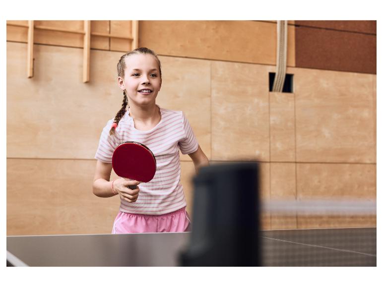 Fille jouant au tennis de table, tenant une raquette rouge.