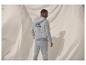 Man in grijze hoodie en joggingbroek met 'Sunday Couching Club'-logo.