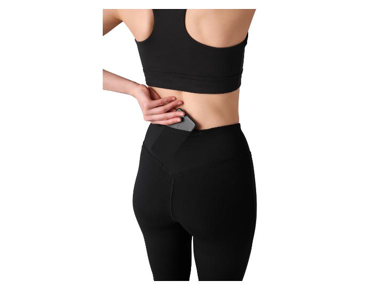 Femme en brassière de sport noire et legging avec téléphone dans la poche