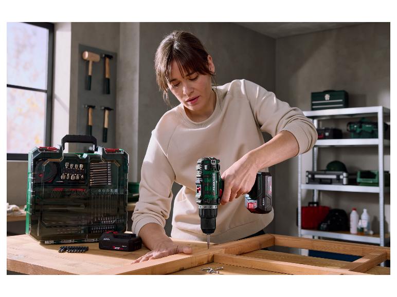 Vrouw gebruikt accuboormachine om houten frame te monteren, naast een bitset.