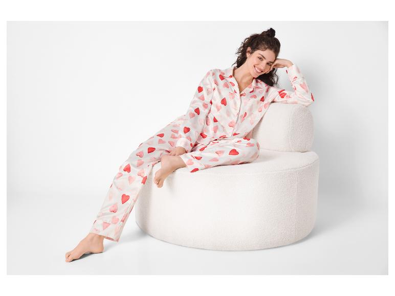 Vrouw in witte pyjama met rode harten, zittend op een witte fauteuil.