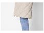Lange, beige gewatteerde jas met jeans.