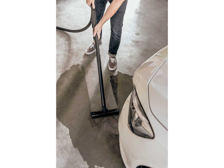 Un homme nettoie le sol d'un garage avec un nettoyeur vapeur Kärcher.