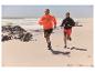 Koppel rent in sportkleding op het strand.