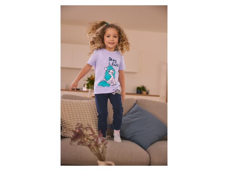 Une fille porte un t-shirt à imprimé licorne et un pantalon bleu.