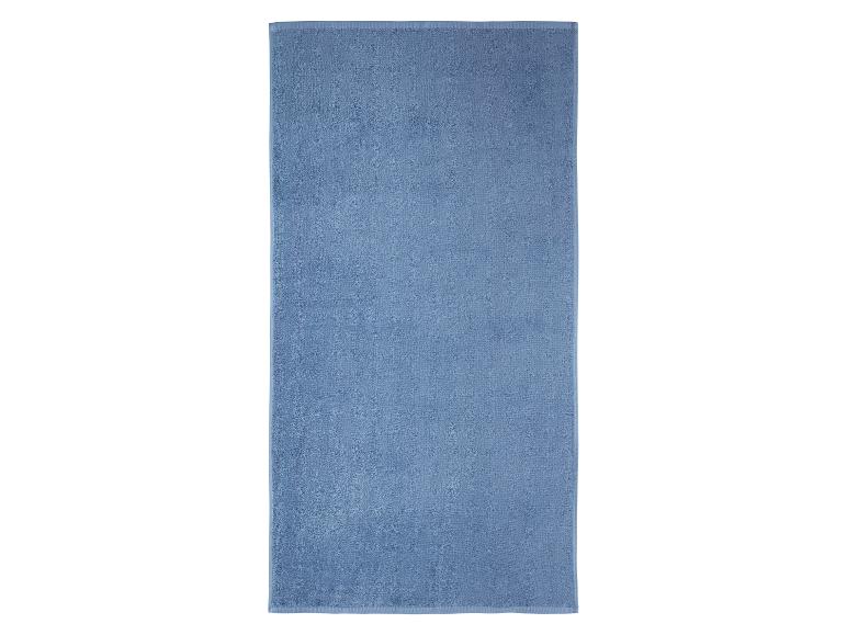 Lichtblauwe badhanddoek, gevouwen, op een witte achtergrond.