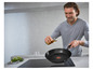 Een man giet olie in een Tefal koekenpan op een inductiekookplaat.