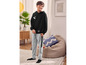 Een jongen draagt een zwarte hoodie met een skateboardprint en grijze sweatpants.