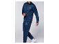 Homme en survêtement bleu marine avec logo vert et bleu, baskets blanches.