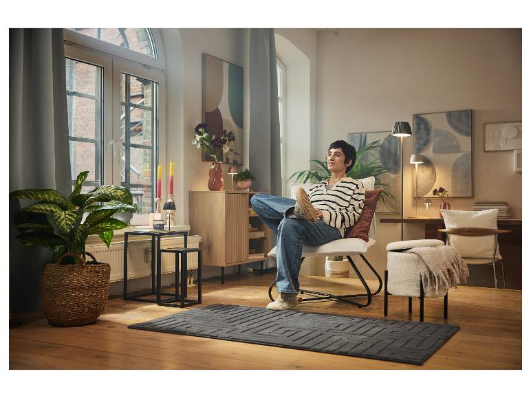 Een vrouw ontspant in een fauteuil in een gezellige woonkamer.