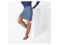 Femme en pull bleu et jupe en jean, bottes hautes brunes.