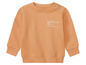 Un pull orange pour bébé avec l'inscription 'future'.