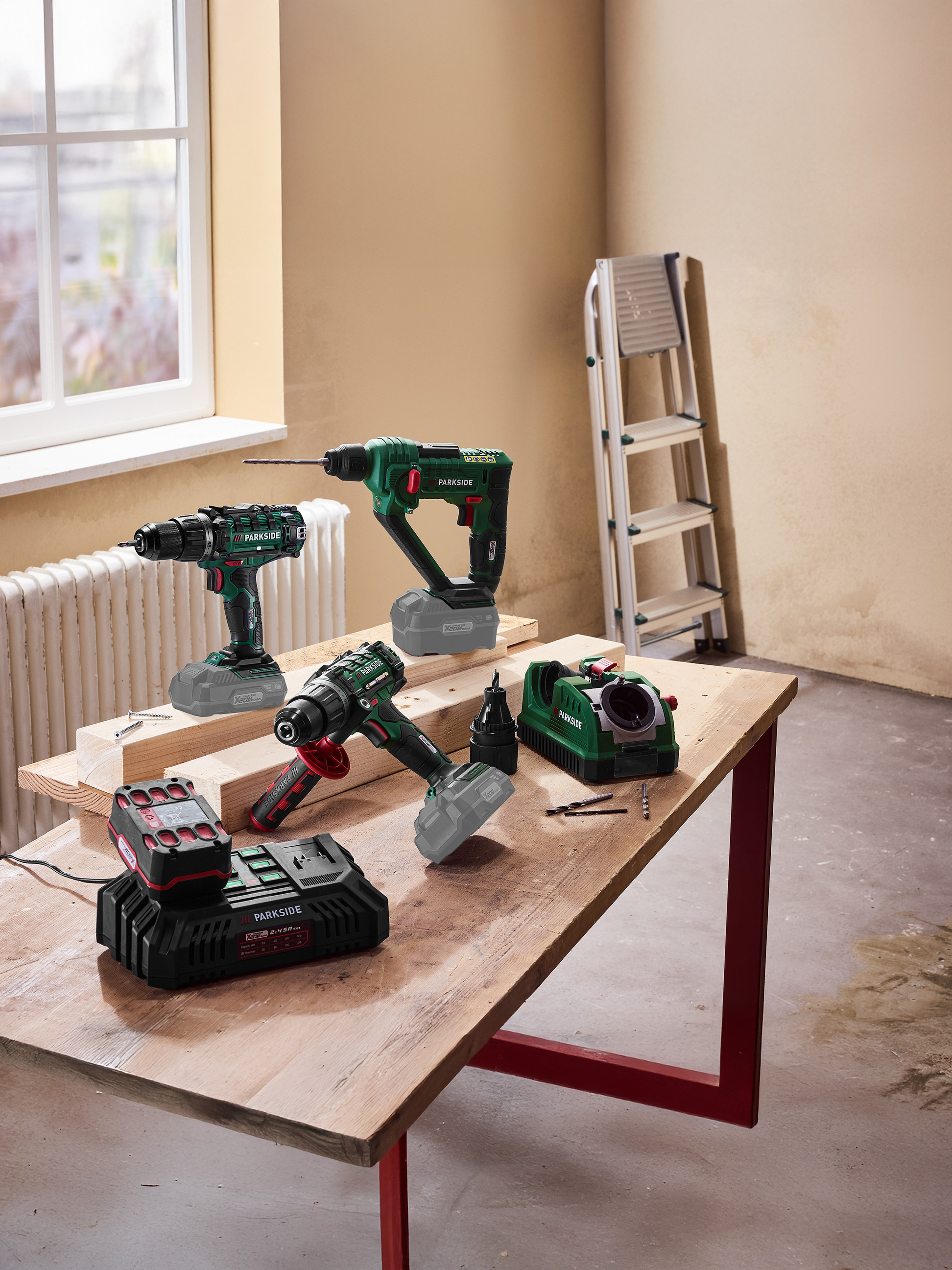 Elektrisch gereedschap, waaronder boormachines en een acculader, op een houten tafel.