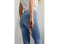 Een vrouw draagt een witte blouse en blauwe jeans.