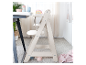 Une chaise haute en bois clair pour enfant près d'une table.