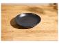 Un bol en céramique noir mat sur une table en bois clair.