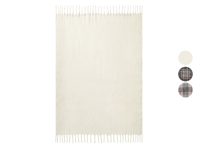 Une couverture blanche avec des franges, avec un exemple de deux motifs de plaid