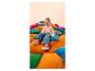 Fille riante en t-shirt rose, cardigan et jean, assise sur des coussins colorés.