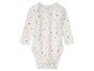 Un body blanc pour bébé avec un imprimé de fleurs et de cœurs.