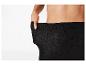 Une personne tire sur la taille d'un legging noir pour montrer qu'il est trop grand.