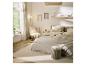 Lichte slaapkamer met bed, vloerkleed, fauteuil en decoratie in natuurlijke tinten.