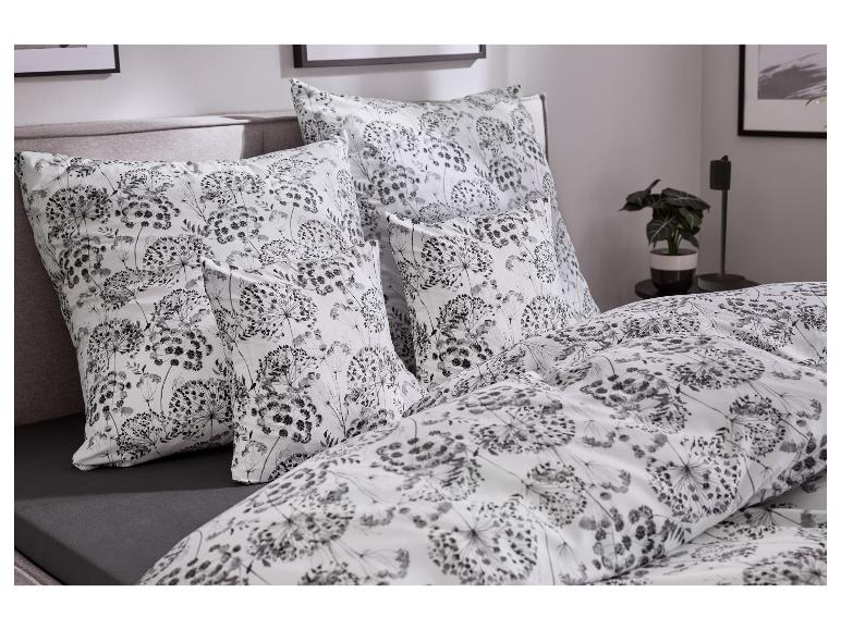 Lit avec housse de couette et oreillers floraux blancs et gris, drap-housse gris foncé.