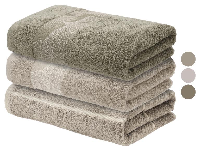 Pile de serviettes en coton beige et vert olive avec motif de feuilles, avec échantillons de couleurs.