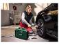 Vrouw pompt de band van een zwarte auto op met een draagbare Parkside compressor.