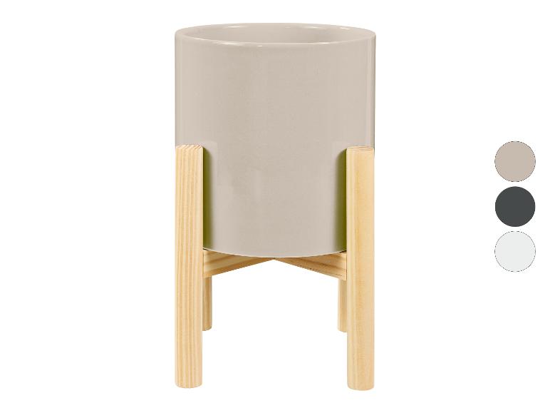 Grijze bloempot met houten standaard.