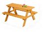 Table de pique-nique en bois pour enfants avec bancs et vaisselle colorée.